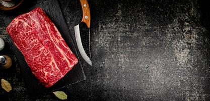 rå nötkött på en sten styrelse med en kniv. foto