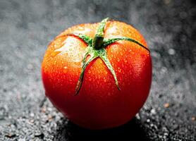 ett mogen tomat med droppar av vatten. foto
