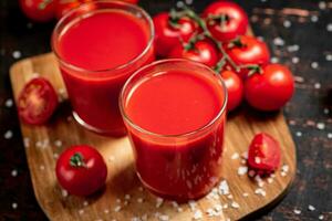 tomat juice i glasögon på en trä- skärande styrelse. foto