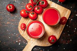 tomat juice i glasögon på en trä- skärande styrelse. foto