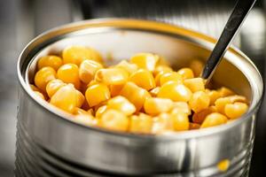 ett öppen kan av konserverad majs med en sked. foto