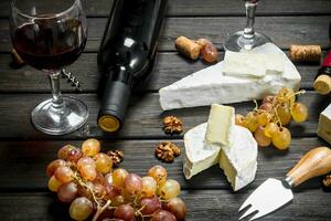 Brie ost med röd vin, nötter och vindruvor. foto