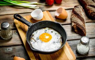 friterad ägg i en panorera med bröd, tomater och grön lök. foto