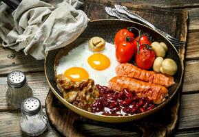 engelsk frukost.stekt ägg med korvar, bacon och röd konserverad bönor. foto