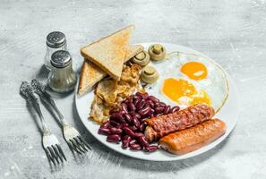 engelsk frukost. friterad ägg med korvar, bacon och bönor. foto