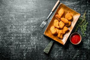 kyckling nuggets på en tallrik med gaffel, sås och timjan. foto