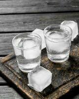 vodka i en skott glas av is på de skärande styrelse. foto