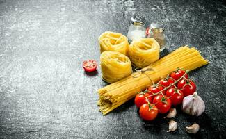 spaghetti och tagliatelle rå med vitlök kryddnejlika och tomater. foto