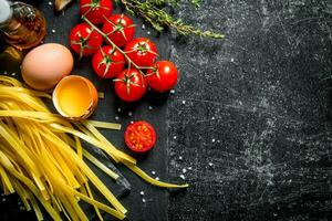 Hem tillverkad rå pasta med timjan, ägg, olja och tomater. foto
