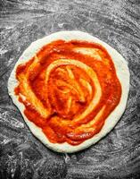 rå pizza. rullad ut deg med tomat klistra. foto
