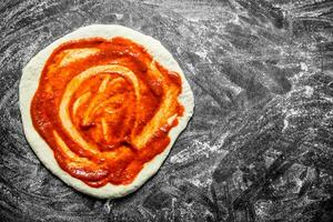 rå pizza. rullad ut deg med tomat klistra. foto