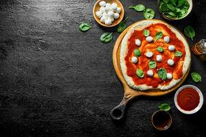 förberedelse pizza. rullad ut deg med tomat klistra, spenat och mozzarella. foto
