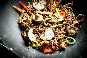 varm asiatisk soba spaghetti med grönsaker, svamp och sås. foto
