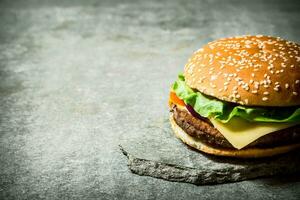 färsk burger med ost och kött på en sten stå. foto