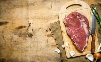 en bit av rå kött med en slaktare kniv och en lök. foto