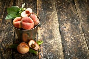 färsk persikor i en hink med löv. foto