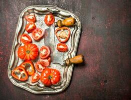 färsk tomater med ett gammal kniv på en stål bricka. foto
