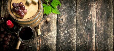 tunna av röd vin med vindruvor och en korkskruv. foto