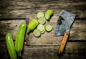 skivad zucchini och ett gammal yxa . foto