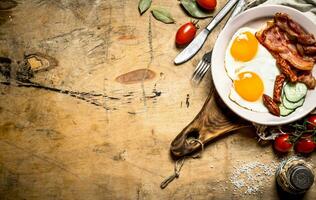 färsk frukost tallrik. friterad ägg med bacon och tomater. foto