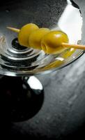 Martini med oliver på en svart tabell. fri Plats för text. foto