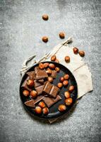 bitar av choklad med nötter på de gammal tallrik. foto