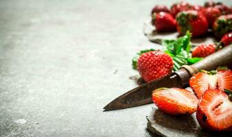 jordgubbar med löv och ett gammal kniv. foto
