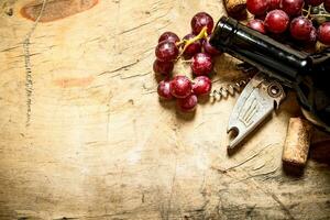 röd vin med en korkskruv, vindruvor och korkar. foto