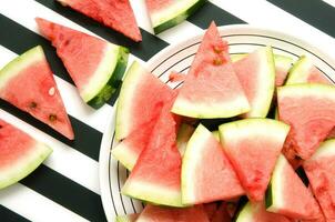 färsk röd vattenmelon skiva i tallrik på randig bakgrund. sommar begrepp. topp se, platt lägga. - bild foto