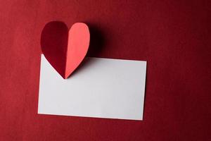 rött hjärtapapper och tomt med anteckningskort på röd bakgrund.