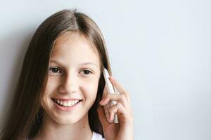 leende tonåring flicka talande på en vit tryckknapp telefon foto