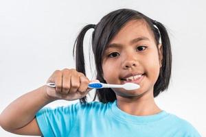 liten flicka borstar tänderna i studio skott foto