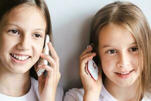 två glad flickor är talande på vit gammaldags tryckknapp telefoner foto