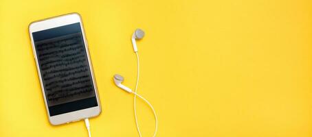 lyssnande till musik använder sig av en smartphone och trådbunden hörlurar. fritid med prylar. topp se. webb baner foto