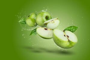 vatten stänk på grön äpple och skära skiva med utsäde på grön bakgrund. foto
