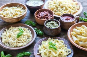 pasta med annorlunda typer av sås på de trä- bakgrund foto