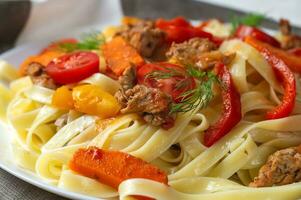 fettuccine med friterad kött, morötter, klocka paprika, dill tomater. pasta med grönsaker. närbild foto