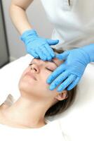 kvinna tar emot ansikte behandling förbi kosmetolog i skönhet salong foto