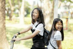 glad asiatisk tonåring lycka känsla ridning cykel i offentlig parkera foto