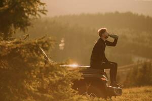 ung man avkopplande på en terräng fordon huva på landsbygden foto