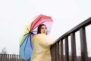 kvinna som står utomhus med ett färgat paraply och tittar bort foto
