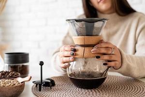 kvinna som brygger kaffe i kaffekanna, häller varmt vatten i filtret foto