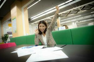 skön asiatisk företag kvinna Sammanträde och fira med lycka på henne skrivbord. foto