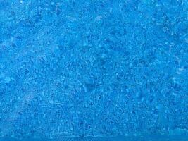 yta av blå simning slå samman botten kaustik krusning och strömma med vågor bakgrund. ljus blå rev vatten i simning slå samman, sommar bakgrund. textur av vatten yta. topp se. foto