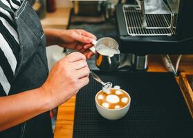hand av en Barista i de kaffe affär framställning till ånga mjölk i de kanna för en kaffe cappuccino meny. foto