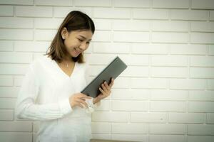 skön asiatisk kvinna lärare ser och innehav läsplatta till inlärning något ny för undervisning med studenter. foto