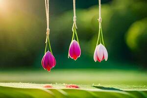 tre rosa tulpaner hängande från strängar på en grön gräs. ai-genererad foto