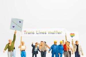 miniatyr folk demonstrant håller en transgender flagga