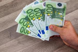 mans hand som rymmer 100 euro -sedlar foto