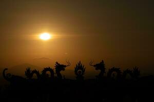 en solnedgång med drake statyer i de bakgrund foto